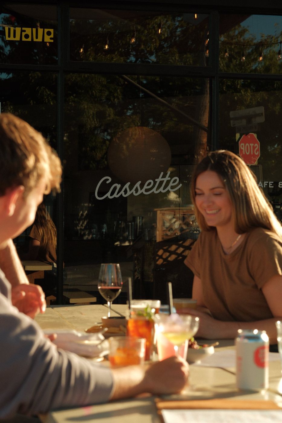 Friends sharing drinks and snacks on the patio in front of the Cassette window